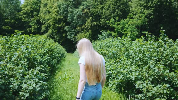 Back View of Blonde Young Woman Walking in Natural Park