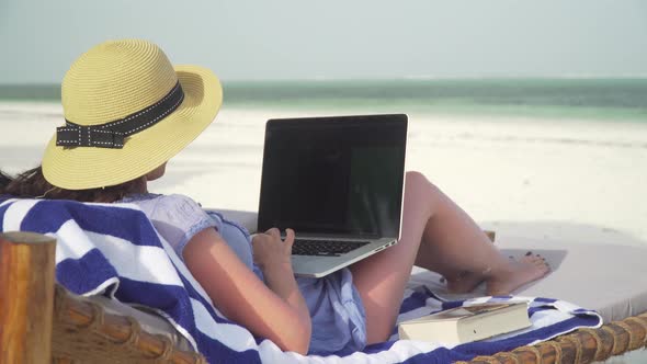 Young Woman Uses Laptop On White Beach Near Ocean