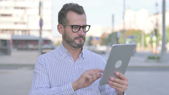 Young Adult Man Celebrating Success on Tablet Outdoor