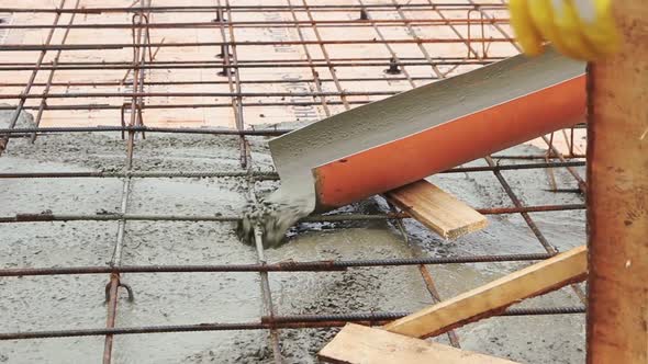 Pouring concrete mixture to the reinforcing mesh and a house foundation