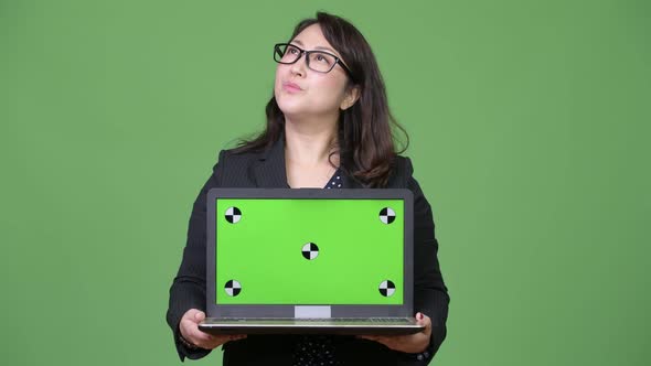 Mature Beautiful Asian Businesswoman Showing Laptop Against Green Background