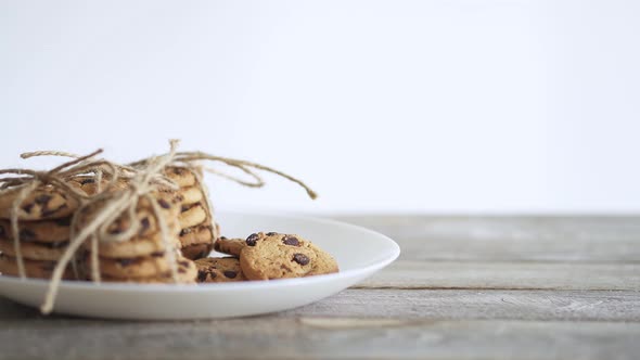 Male Hand Takes A Biscuit Pastry. Chocolate Chip Cookies On A White Plate