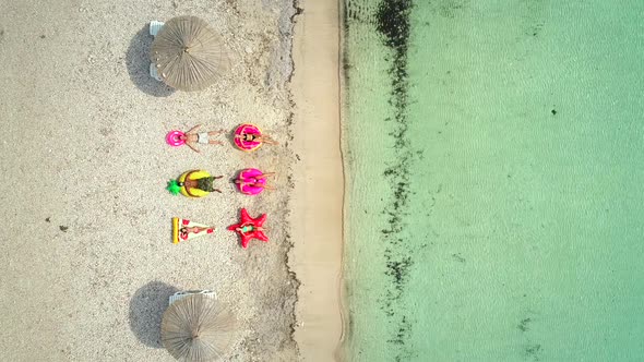 Aerial view of people lying on big inflatable mattresses on beach.