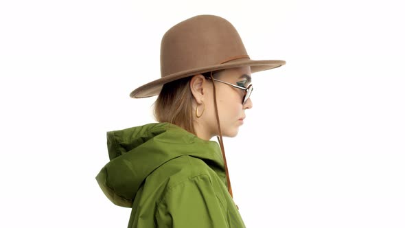 Woman in a Autumn Look in Studio in Green Parka and Hat Turns and Poses To the Camera