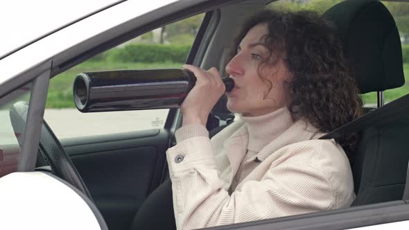 Woman is Drinking Wine While Sitting in Her Car