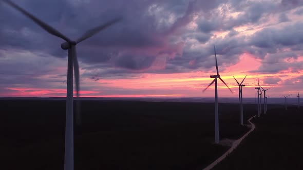 Wind Turbine Farm on Beautiful Purple Evening Mountain Landscape. Renewable Energy Production for