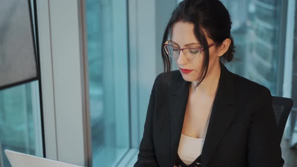 Portrait of an Attractive Business Woman Wearing Glasses Working at a Computer in a Modern Office