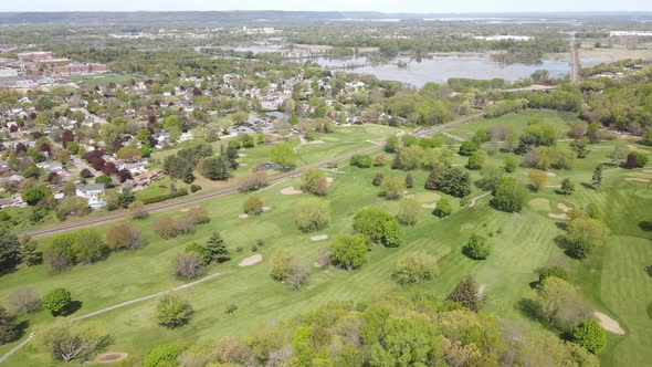 Gorgeous aerial view over golf course and rural community on edge of wetland with mountains in view.