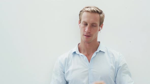 Portrait of Man Putting on Wireless Headphones Listening to Music Dancing