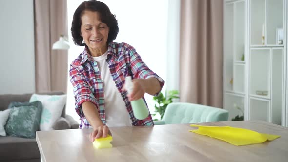 Happy American Woman Is Wiping Table with Sponge Standing in Home Living Room