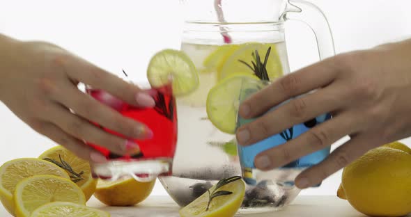 Woman and Man Hands Takes Refreshing Soda Red and Blue Cocktails with Lemon