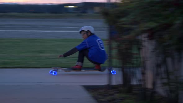 A boy rides a skateboard with led lights wheels in a neighborhood.