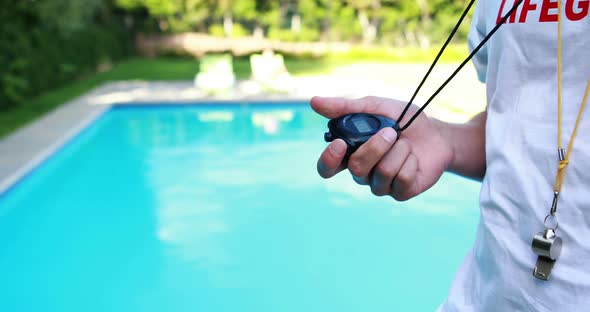 Lifeguard looking at stopwatch near the poolside