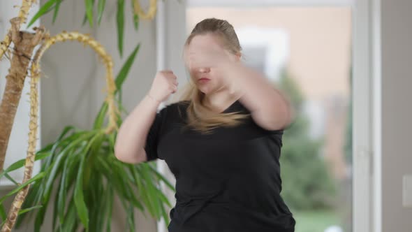 Middle Shot Portrait of Serious Concentrated Chubby Sportswoman Boxing Shadow Indoors