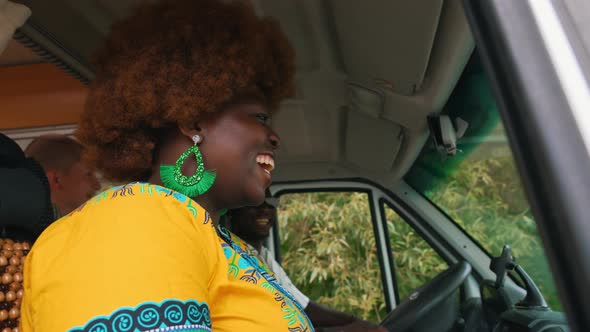 Darkskinned Smiling African Young Woman with Afro Haircut Wearing a Bright Boho Outfit Looking Out