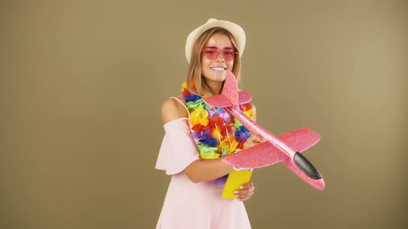 Lady in Hawaiian Lei is Smiling Holding Passport and Tickets Playing with Flying Toy Airplane and