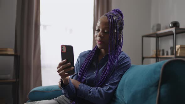 Young Black Woman is Chatting By Video Call in Mobile Phone Sitting Alone at Home at Weekend Talking