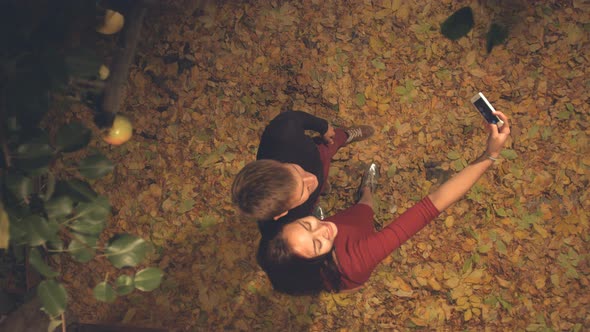 Young Couple in Leaves are Photographed Themselves