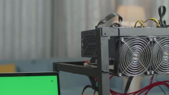 Close Up Of Green Screen Laptop And Mining Rig On The Table For Cryptocurrency Mining