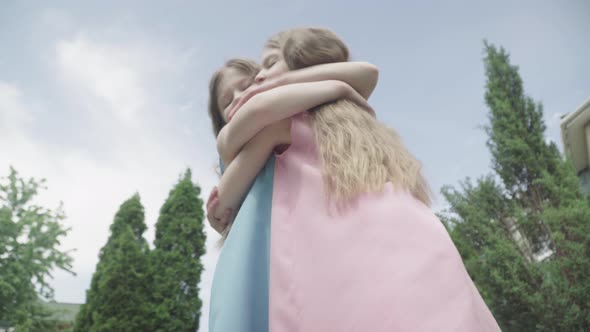 Bottom View of Charming Little Twins Hugging at the Background of Blue Summer Sky. Smiling Caucasian