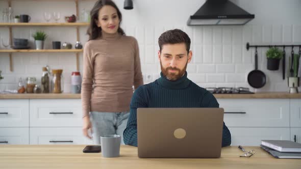 Husband Working Online on Laptop Then Wife Comes Up Talking to Him at Kitchen