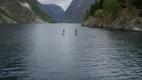 Two People on SUP Baddle Board in Norwegian Fjord