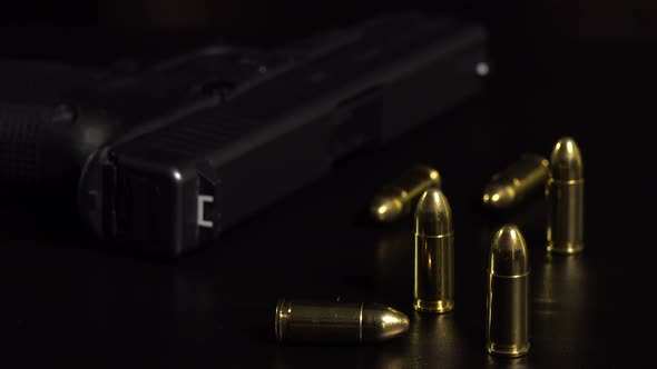 Closeup on Bullets and a Gun on a Black Table