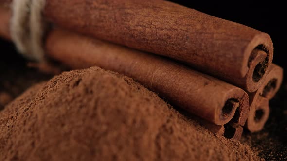 Cinnamon sticks and cinnamon powder isolated on black background, sliding shot