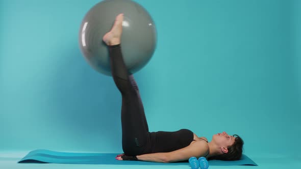 Young Adult Lifting Fitness Toning Ball to Train Legs Muscles