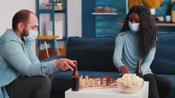 Multiethnic Concentrated Friends Playing Chess Game Sitting on Couch