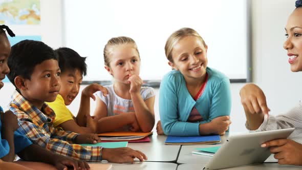 Teacher teaching school kids on digital tablet in classroom