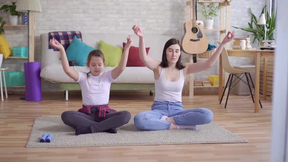 Mother and Daughter Doing Yoga Sitting on the Floor