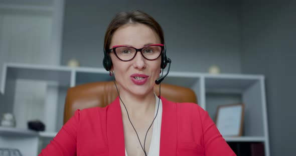 Woman Wear Headset Communicating by Conference Call Speak Looking at Computer at Home Office