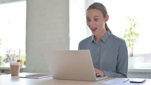 Woman Celebrating Success While Using Laptop in Office