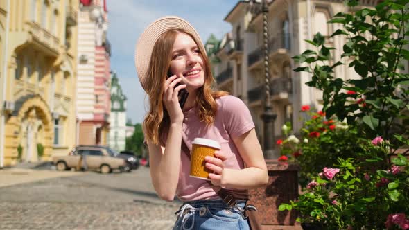 Beautiful Young Woman Tourist with Takeout Coffee in the City Center Talking on the Phone