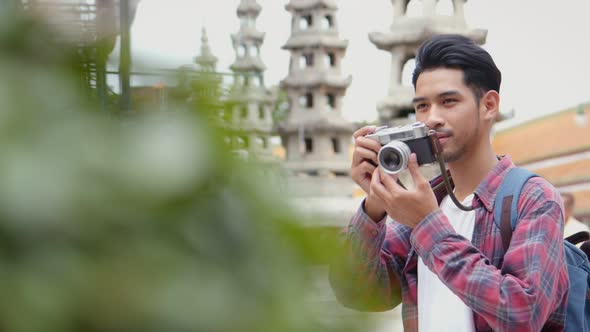 Asian man tourists walking traveling and using film camera taking a photo in temple Thailand.