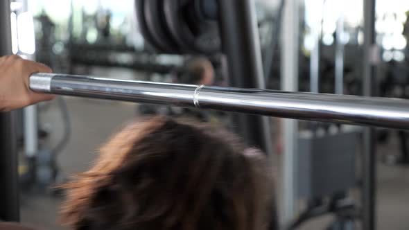 Woman in Sportswear is Going to Do Squats with Barbell Back View