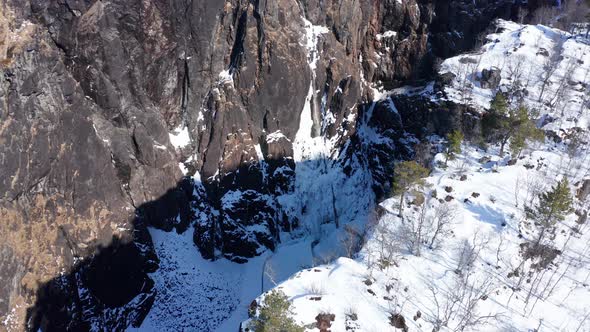 Stunning winter aerial flying over the cliffs, revealing spectacular frozen vøringsfossen far down i