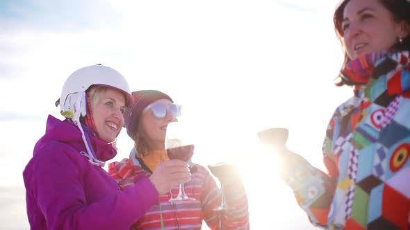 Three Caucasian Females in Ski Suits Smiling Laughing Drinking Wine From Glasses in Slowmotion
