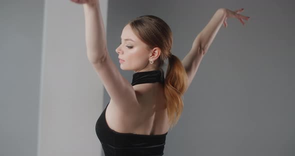 Attractive Young Woman Dancer in Black Dress with Open Back Rehearses Dance Moves, Ballet Rehearsal