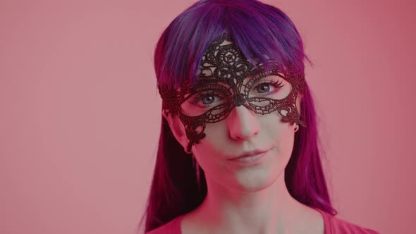 Mysterious Caucasian Woman in a Lace Mask Looking Intensively Into the Camera Closeup Shot Pink