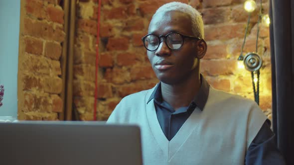 African American Man Having Coffee and Using Laptop in Cafe