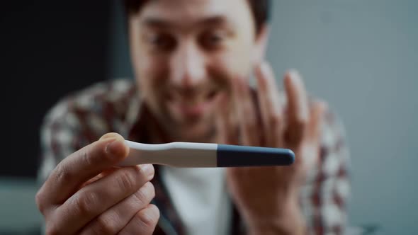 One Happy and Joyful Caucasian Man Holding Pregnancy Test at Home