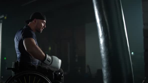 Slow Motion Disabled Man Fighter in Wheelchair Man Trains Punches on a Punching Bag Training in the