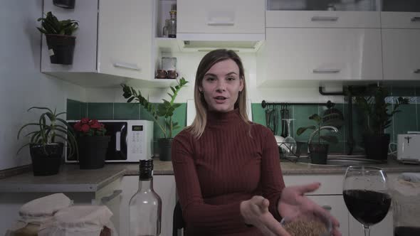 Young Attractive Housewife Writes Video Recipes in Kitchen at Home for Her Blog and Raises Glass of