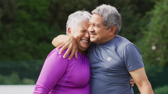 Video of happy biracial senior couple embracing during training on tennis court