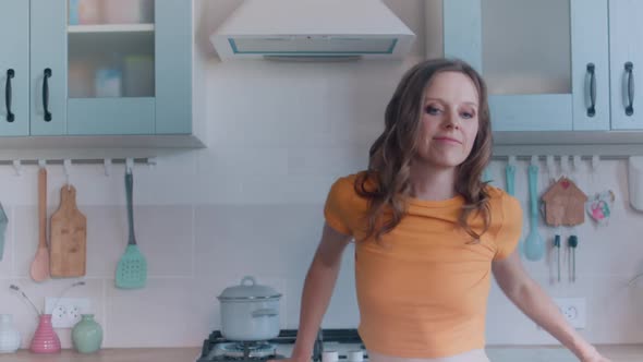 A Beautiful Woman in White Shorts is Relaxing at Home Dancing in the Kitchen