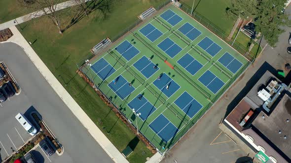 Orbiting Drone Shot of People Playing Tennis in a Park on a Sunny Day