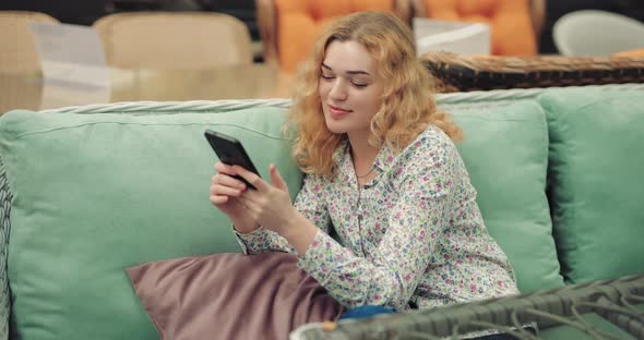 Coquette Woman Using Smartphone Sitting on Green Sofa