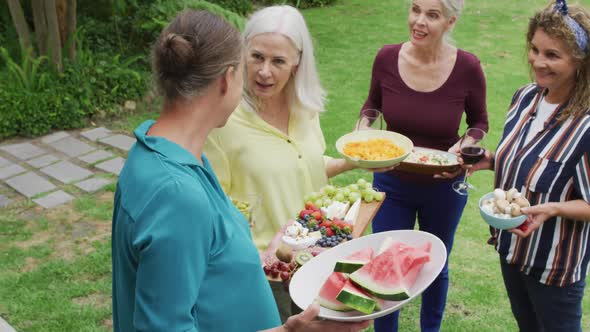 Animation of happy diverse female and male senior friends preparing lunch in garden